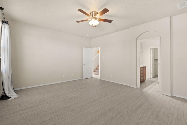 empty room with ceiling fan, light hardwood / wood-style floors, and a textured ceiling