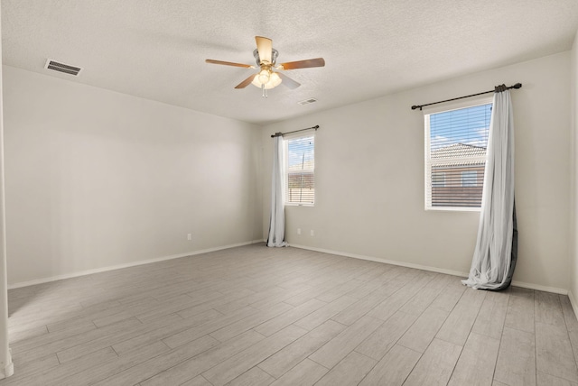 empty room with ceiling fan, light wood-type flooring, and a textured ceiling