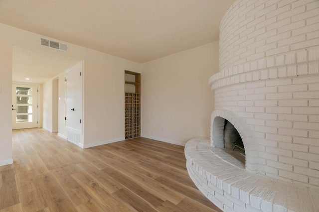 unfurnished living room featuring a brick fireplace and light hardwood / wood-style flooring