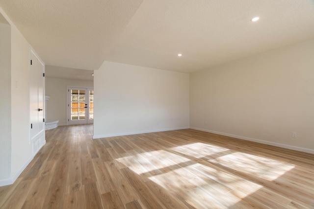 unfurnished room featuring french doors, a textured ceiling, and light wood-type flooring