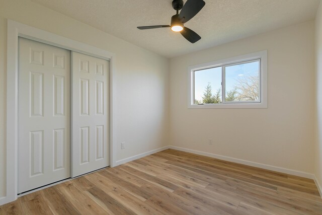 unfurnished bedroom featuring light hardwood / wood-style floors, a textured ceiling, ceiling fan, and a closet