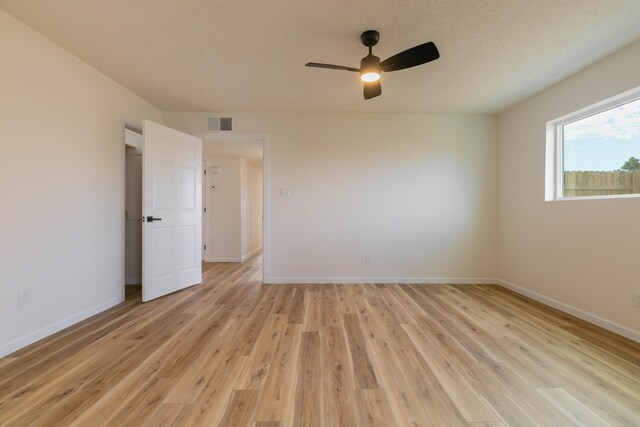 spare room with ceiling fan, a textured ceiling, and light wood-type flooring