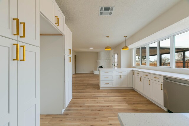 kitchen featuring pendant lighting, sink, appliances with stainless steel finishes, white cabinetry, and wall chimney exhaust hood