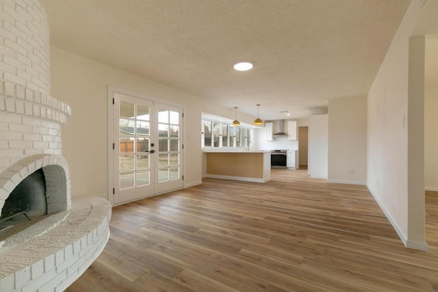 living room featuring dark wood-type flooring, a brick fireplace, french doors, and a textured ceiling