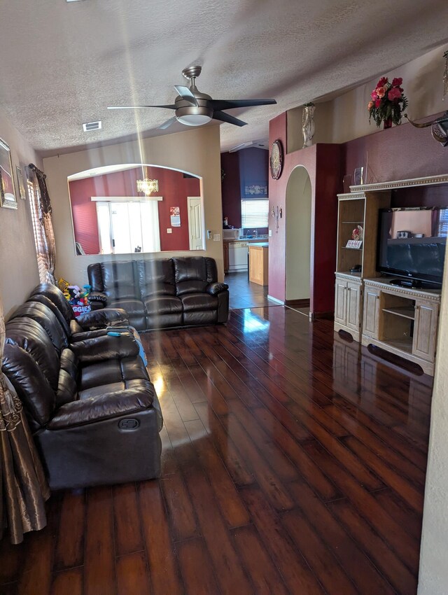 living room featuring vaulted ceiling, wood-type flooring, and ceiling fan with notable chandelier