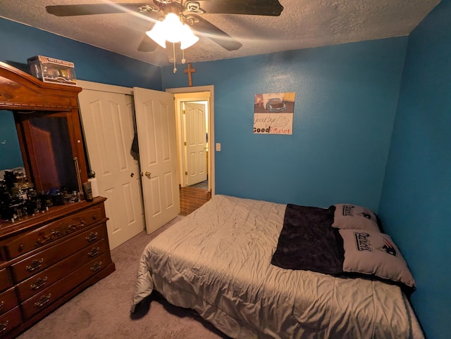 carpeted bedroom with a textured ceiling, a closet, and ceiling fan