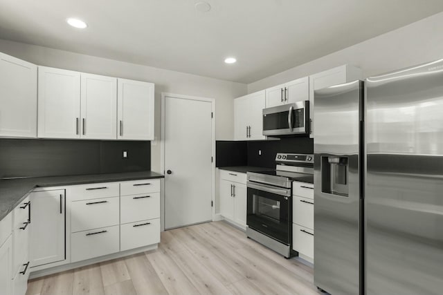 kitchen featuring light hardwood / wood-style floors, stainless steel appliances, white cabinetry, and backsplash