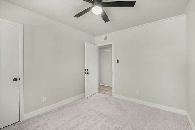 carpeted spare room with ceiling fan and crown molding