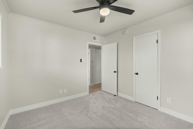 unfurnished bedroom featuring ceiling fan, crown molding, and light carpet