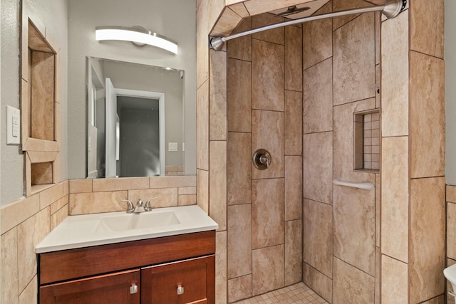 bathroom featuring tasteful backsplash, tiled shower, and vanity