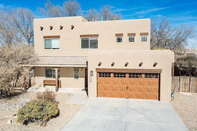 pueblo revival-style home featuring covered porch and a garage