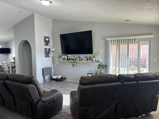 living room with wood-type flooring, a textured ceiling, and lofted ceiling