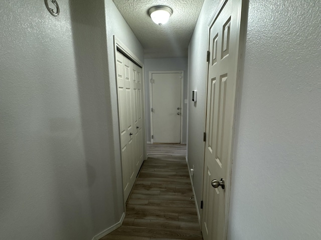 hallway featuring dark hardwood / wood-style floors and a textured ceiling