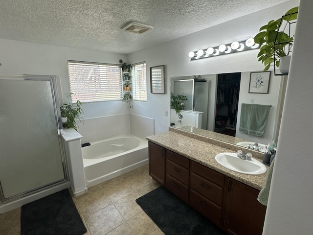 bathroom featuring plus walk in shower, a textured ceiling, vanity, and tile patterned floors