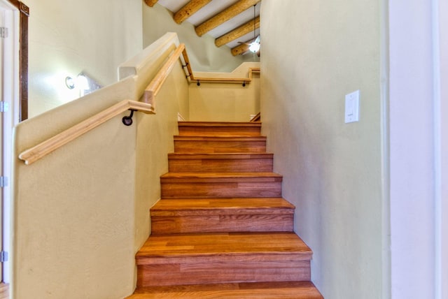 stairway featuring beam ceiling and wood-type flooring