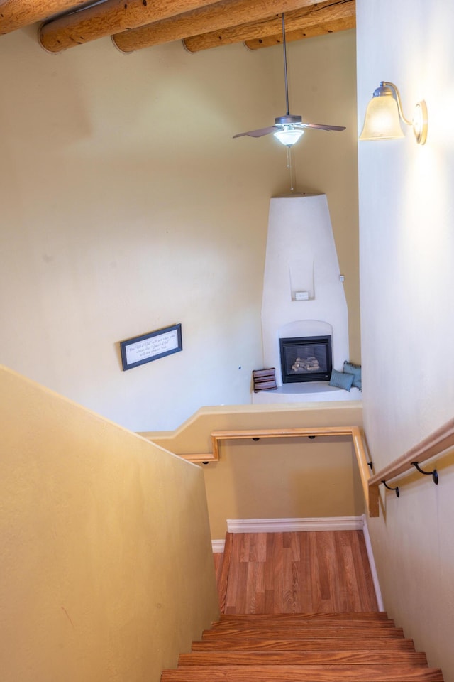 staircase featuring hardwood / wood-style floors, ceiling fan, and beam ceiling