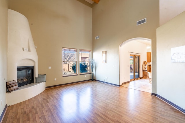 unfurnished living room with a high ceiling and light wood-type flooring