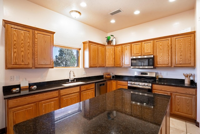 kitchen with light tile patterned flooring, dark stone countertops, sink, and appliances with stainless steel finishes