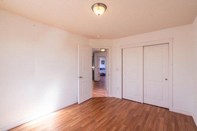 unfurnished bedroom with hardwood / wood-style flooring and a closet