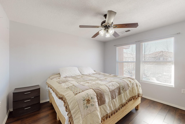 bedroom featuring dark hardwood / wood-style flooring, a textured ceiling, and ceiling fan