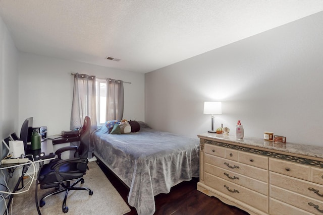 bedroom with dark hardwood / wood-style flooring and a textured ceiling