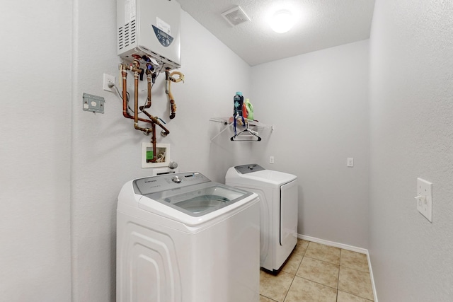 clothes washing area with water heater, light tile patterned floors, and independent washer and dryer