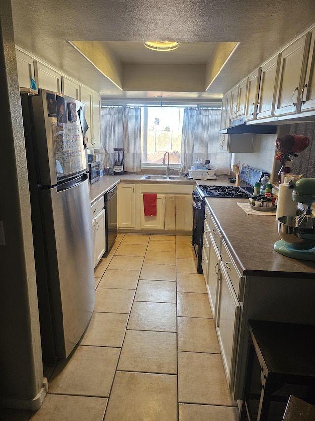 kitchen with dishwasher, a raised ceiling, stainless steel fridge, light tile patterned floors, and gas stove