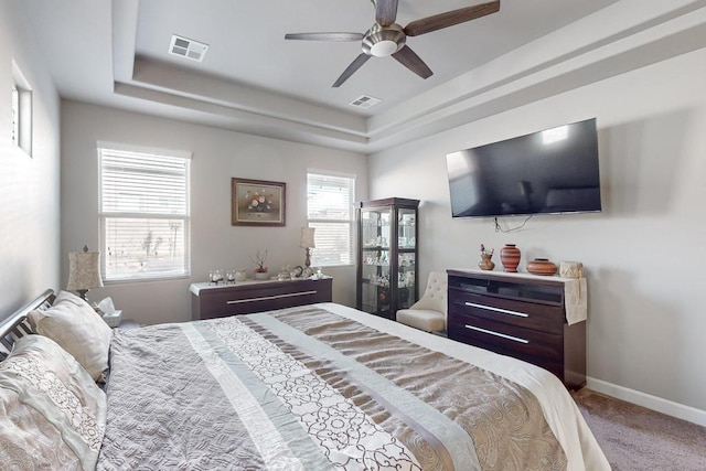 bedroom with carpet flooring, a raised ceiling, and ceiling fan