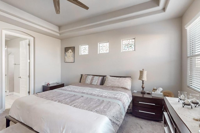 bedroom featuring ceiling fan, light carpet, connected bathroom, and multiple windows