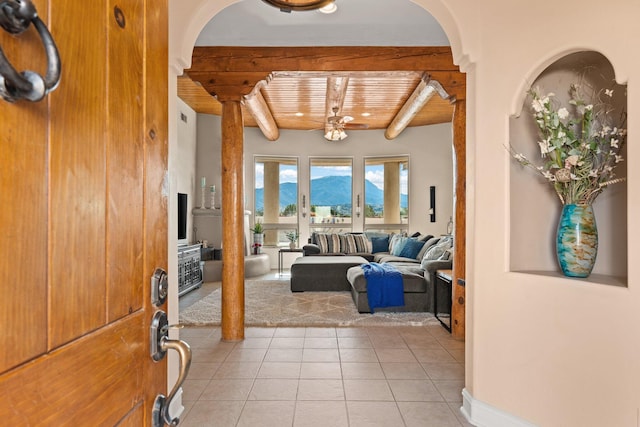 entryway with arched walkways, wooden ceiling, light tile patterned flooring, and beam ceiling