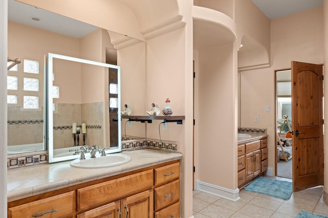 bathroom featuring tile patterned flooring, a tile shower, and vanity