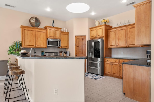 kitchen featuring stainless steel appliances, visible vents, a peninsula, and a breakfast bar area