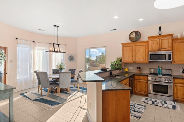 kitchen with stainless steel appliances, visible vents, backsplash, a sink, and a peninsula