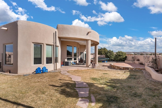 rear view of property featuring a patio area, a lawn, a fenced backyard, and stucco siding