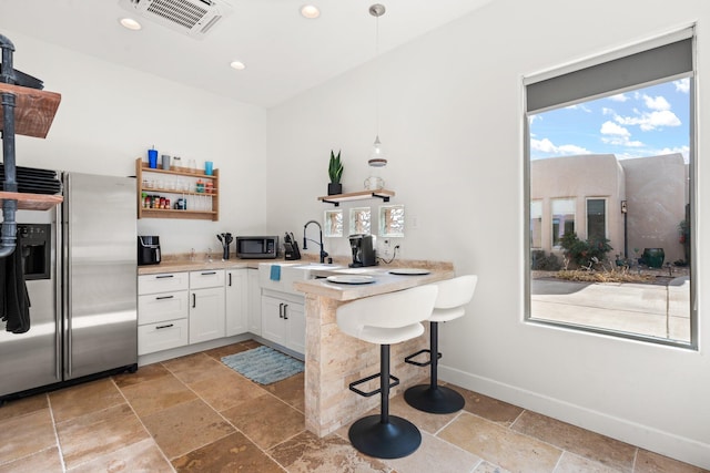 kitchen with baseboards, visible vents, stainless steel appliances, stone tile flooring, and open shelves