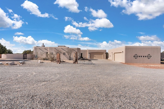 pueblo revival-style home featuring driveway, an attached garage, and stucco siding