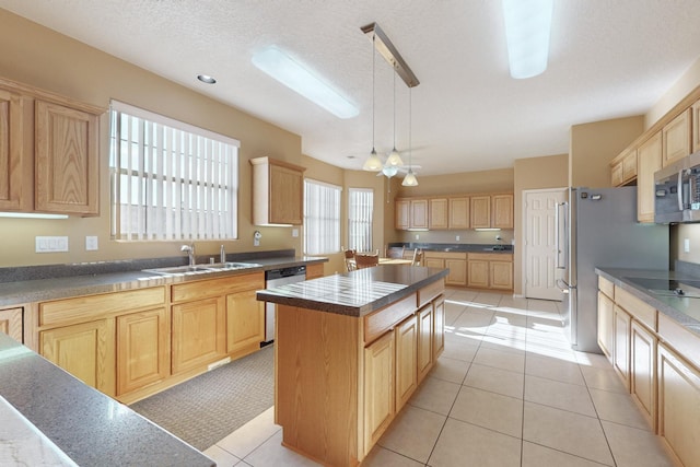 kitchen with sink, appliances with stainless steel finishes, hanging light fixtures, a center island, and light brown cabinets