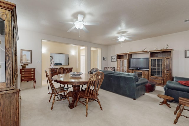 carpeted dining space with ceiling fan