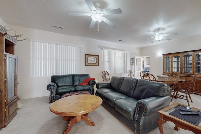 living room featuring ceiling fan, light colored carpet, and a textured ceiling