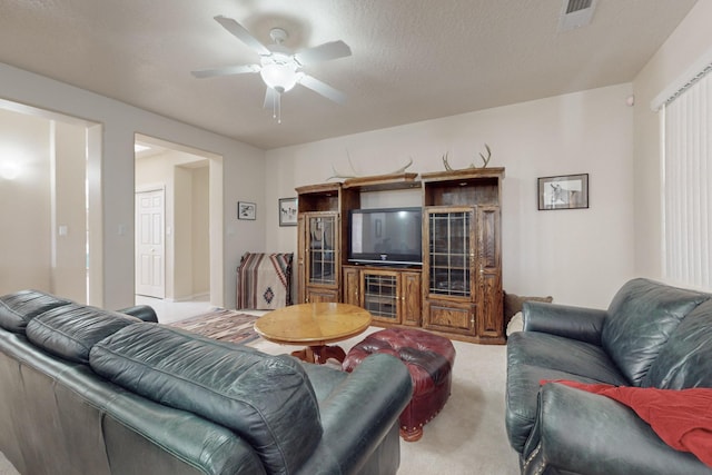 carpeted living room featuring ceiling fan and a textured ceiling