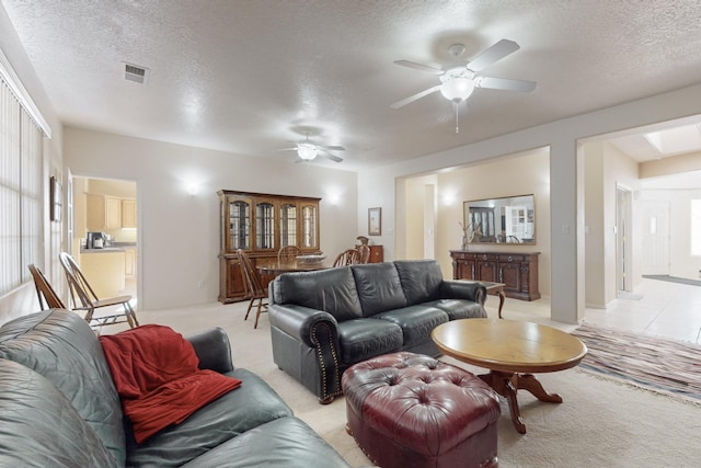 living room featuring ceiling fan, light carpet, and a textured ceiling