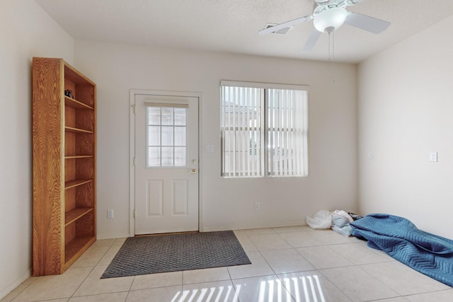 doorway featuring ceiling fan and light tile patterned floors