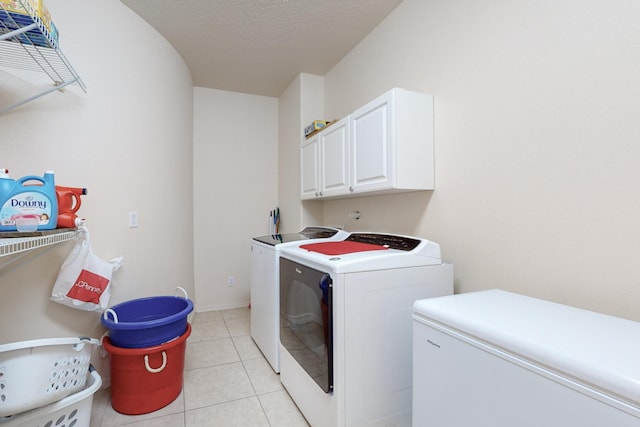 laundry area with cabinets, washer and clothes dryer, a textured ceiling, and light tile patterned floors