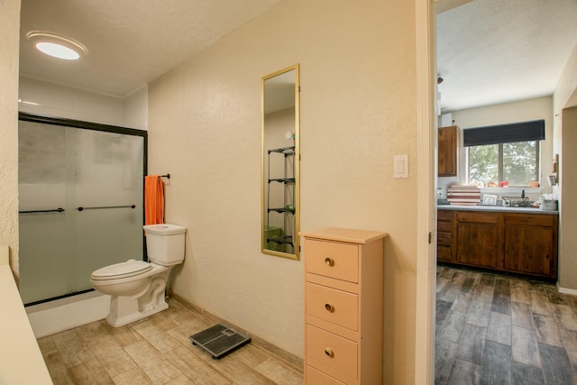 bathroom with hardwood / wood-style floors, toilet, and a shower with door