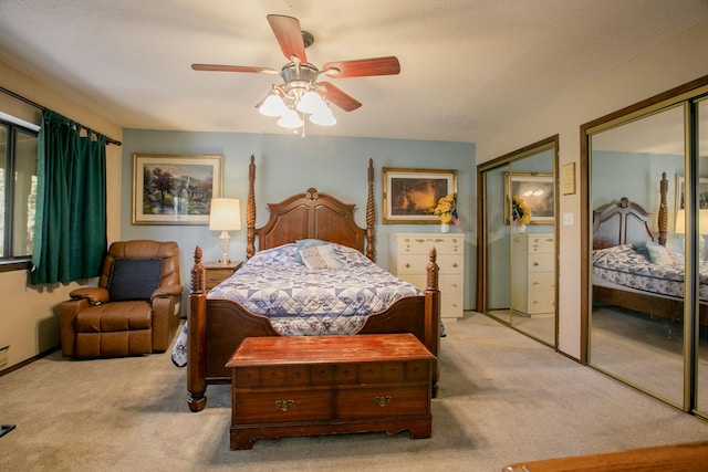 carpeted bedroom featuring ceiling fan and multiple closets