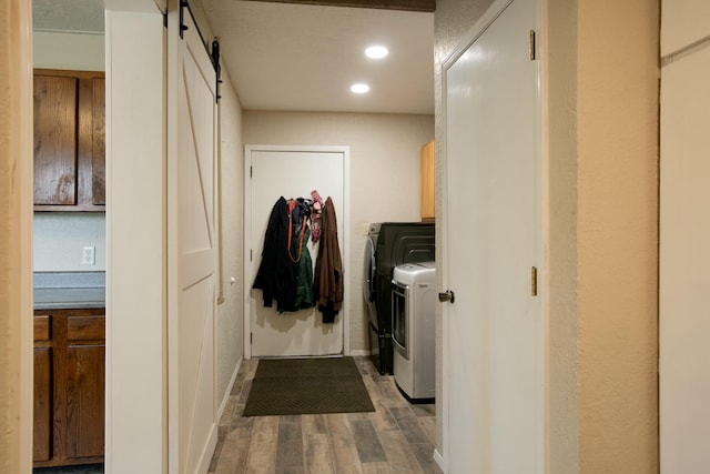 washroom with washing machine and clothes dryer, a barn door, and cabinets