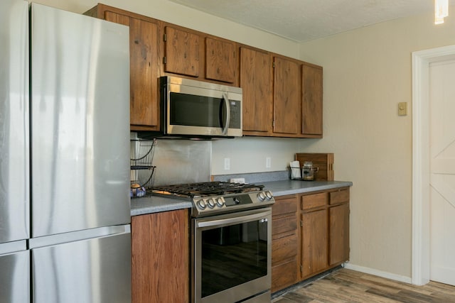 kitchen with appliances with stainless steel finishes and light hardwood / wood-style flooring