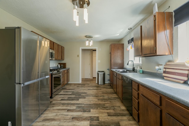 kitchen featuring hardwood / wood-style floors, sink, hanging light fixtures, and appliances with stainless steel finishes