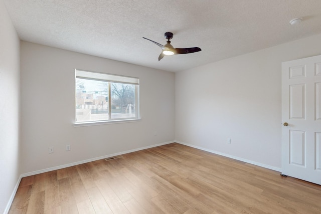 spare room featuring ceiling fan, light wood-type flooring, and a textured ceiling