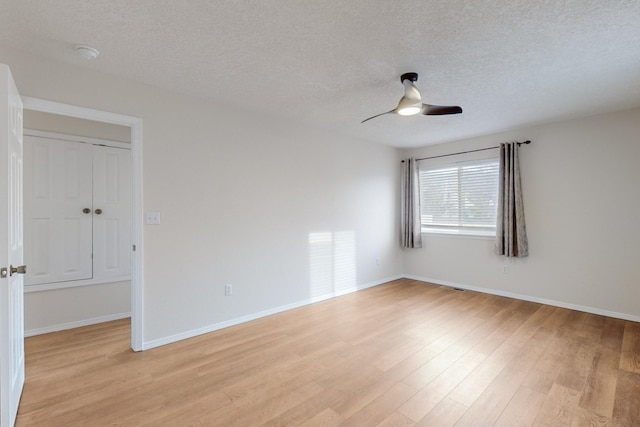 unfurnished room with ceiling fan, a textured ceiling, and light wood-type flooring